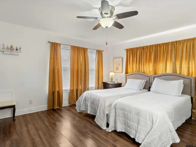 a bedroom with a large bed and a large window with wooden floor