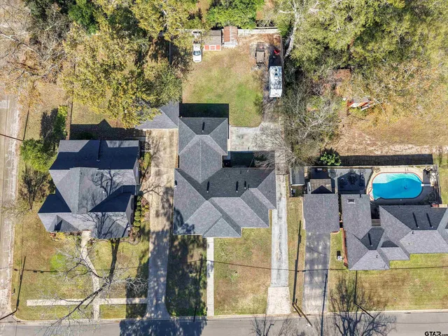 an aerial view of a house with swimming pool and large trees