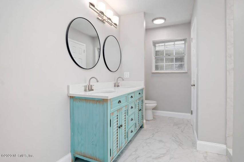 4283 Heath Road Jacksonville, FL 32277 - Photo 23 of 30 a bathroom with a double vanity sink a toilet and a mirror