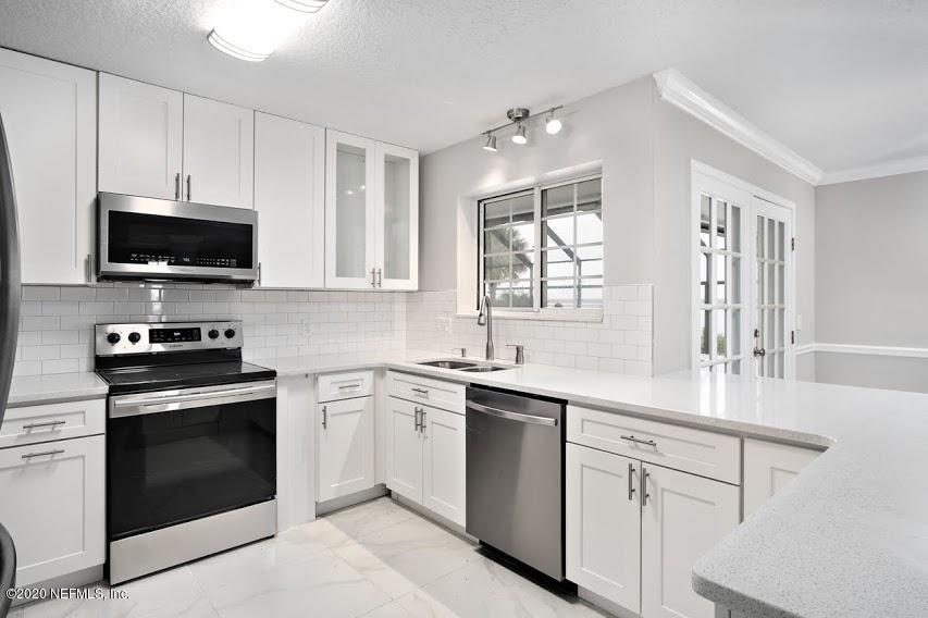 4283 Heath Road Jacksonville, FL 32277 - Photo 10 of 30 a kitchen with white cabinets and stainless steel appliances