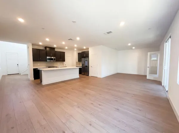 a view of kitchen with kitchen island a sink wooden floor and white stainless steel appliances
