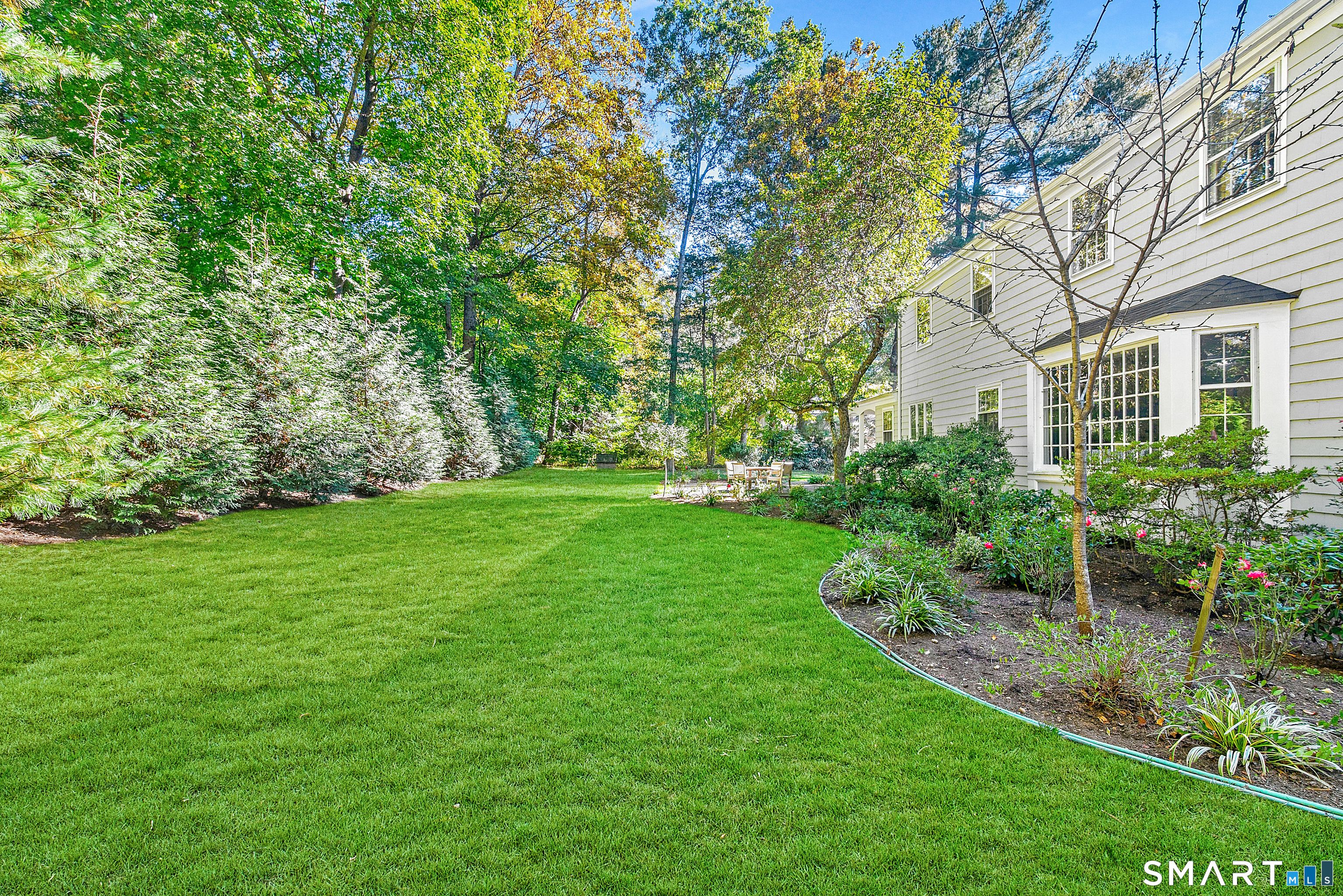 254 White Oak Shade Road New Canaan, CT 06840 - Photo 7 of 31 a view of a white house next to a yard with plants and trees