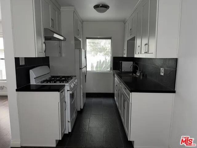 a kitchen with granite countertop a sink a stove and refrigerator