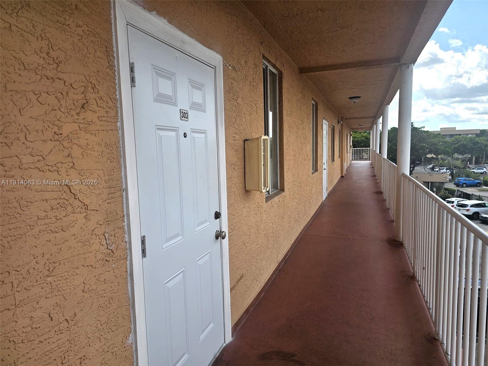 17350 Northwest 67th Avenue, Unit 303 Hialeah, FL 33015 - Photo 5 of 10 a view of a hallway with wooden floor and windows
