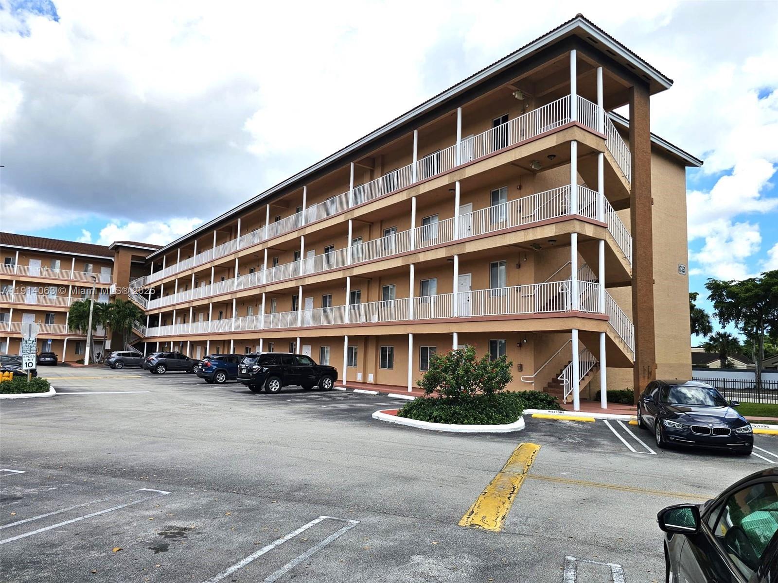 17350 Northwest 67th Avenue, Unit 303 Hialeah, FL 33015 - Photo 7 of 10 a front view of a building with lot of cars and trees