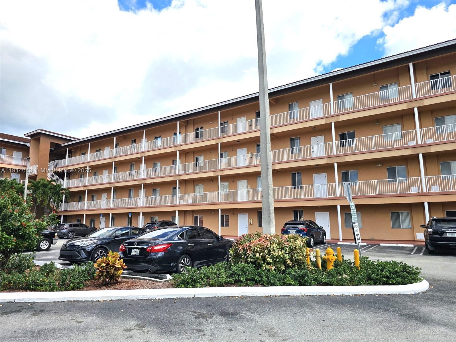 17350 Northwest 67th Avenue, Unit 303 Hialeah, FL 33015 - Photo 9 of 10 a front view of a building with garden