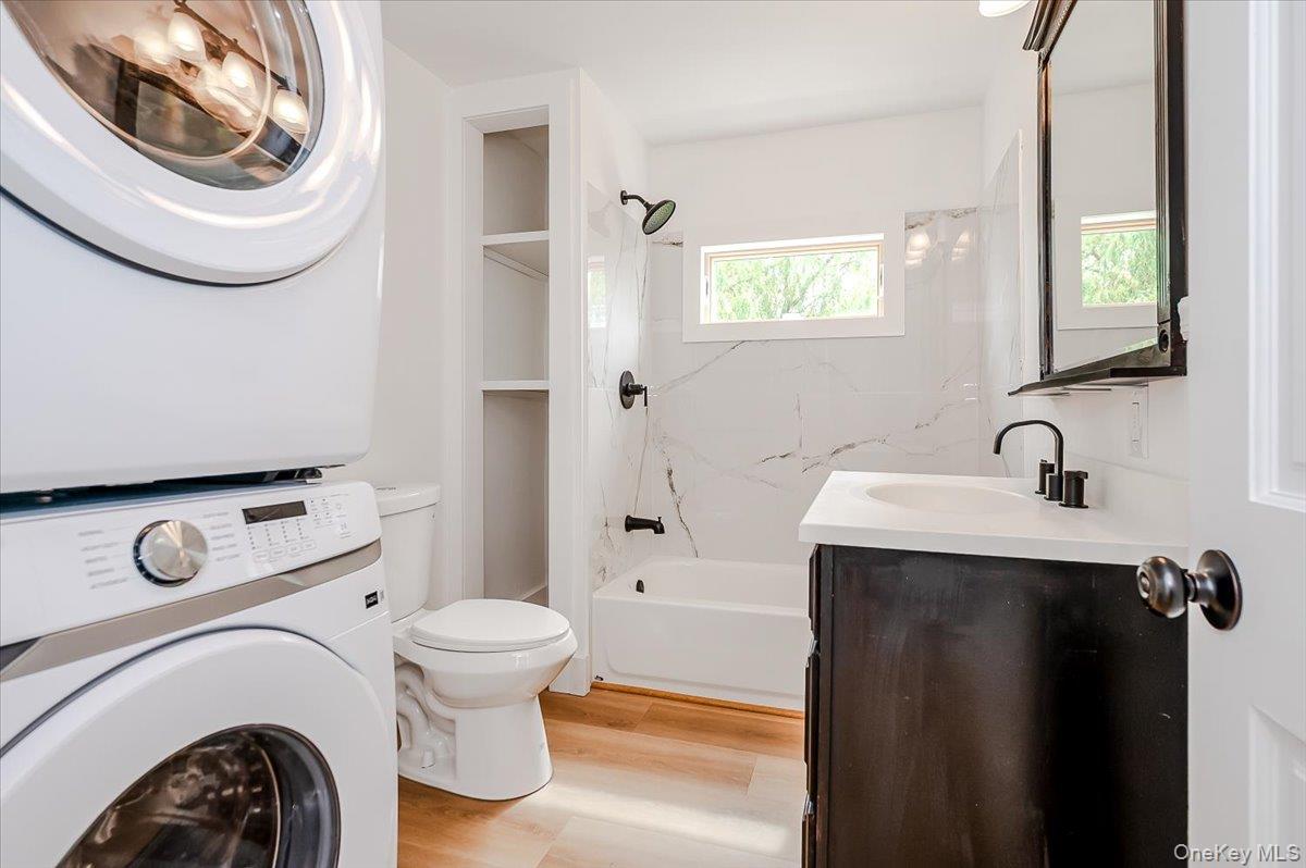 56 Oak Beach Road Babylon, NY 11702 - Photo 24 of 30 Fully renovated second floor bathroom with porcelain wall tiles, stackable washer/dryer, and original refinished wide plank hardwood floors.