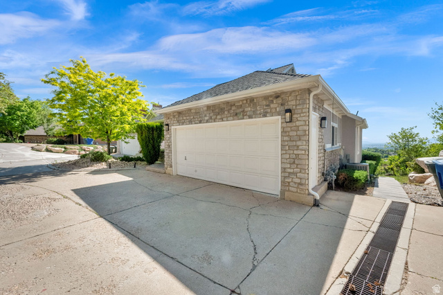 5057 South Ridgedale Drive Ogden, UT 84403 - Photo 5 of 69 Attached garage with a white panel door, stone veneer facade, dual exterior sconces, and a concrete driveway