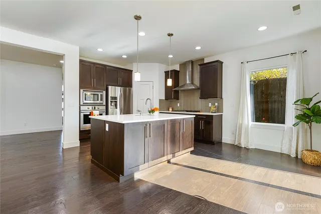 a kitchen with stainless steel appliances kitchen island granite countertop a refrigerator a sink and a stove