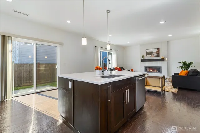 a open kitchen with stainless steel appliances granite countertop a stove a refrigerator a sink dishwasher and a dining table with wooden floor