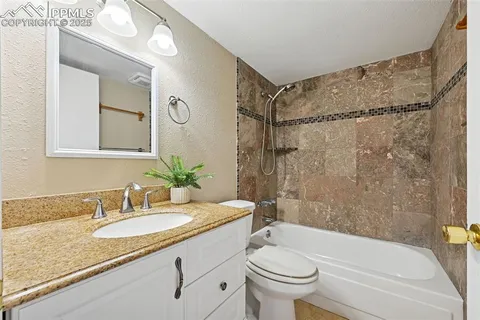 a bathroom with a granite countertop sink a toilet a mirror a bathtub and shower