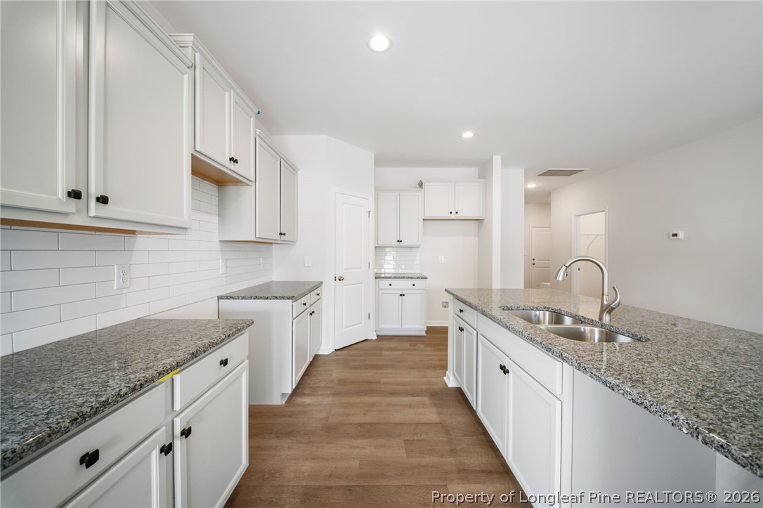 4038 Lofton Street Wade, NC 28395 - Photo 13 of 29 a large kitchen with stainless steel appliances granite countertop a sink dishwasher a stove and white cabinets with wooden floor