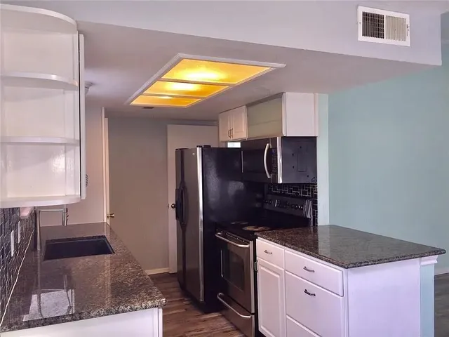 a kitchen with granite countertop a refrigerator and a stove top oven