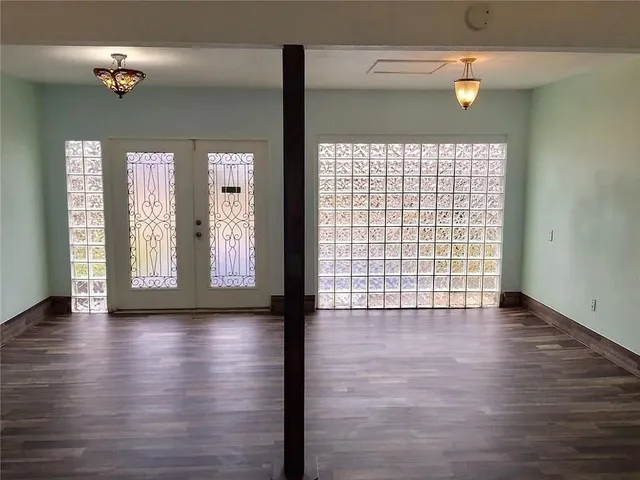 a view of an empty room with wooden floor and a window