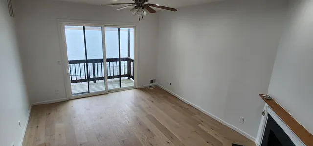 an empty room with wooden floor fan and windows