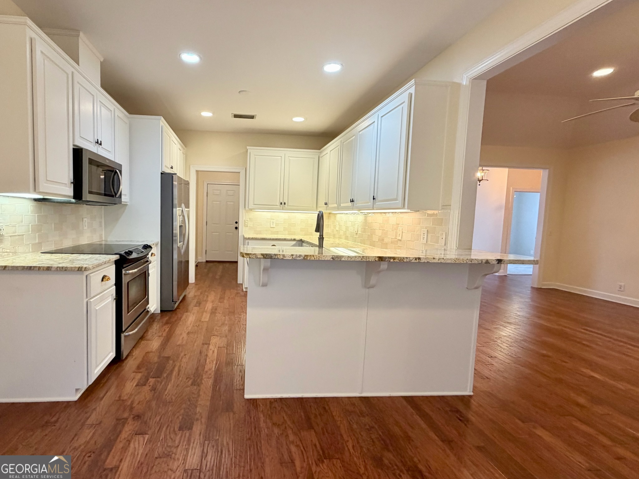 317 Commons Road St. Simons, GA 31522 - Photo 13 of 44 a kitchen with stainless steel appliances granite countertop a refrigerator a stove top oven a sink and dishwasher with wooden floor