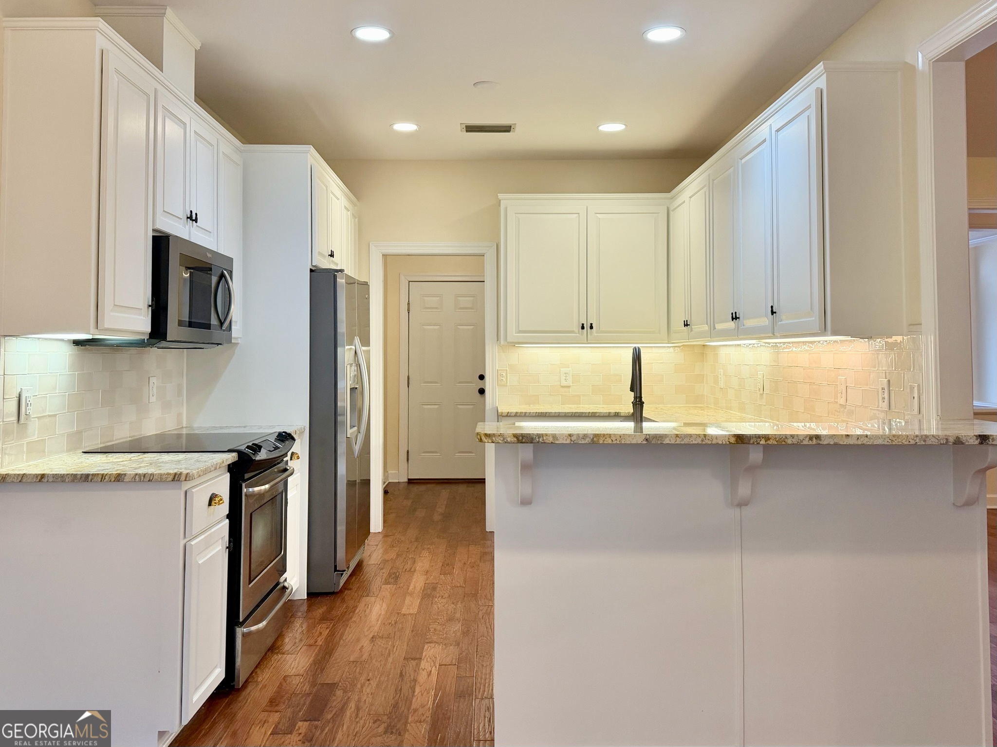 317 Commons Road St. Simons, GA 31522 - Photo 14 of 44 a kitchen with stainless steel appliances granite countertop a stove a sink and a refrigerator