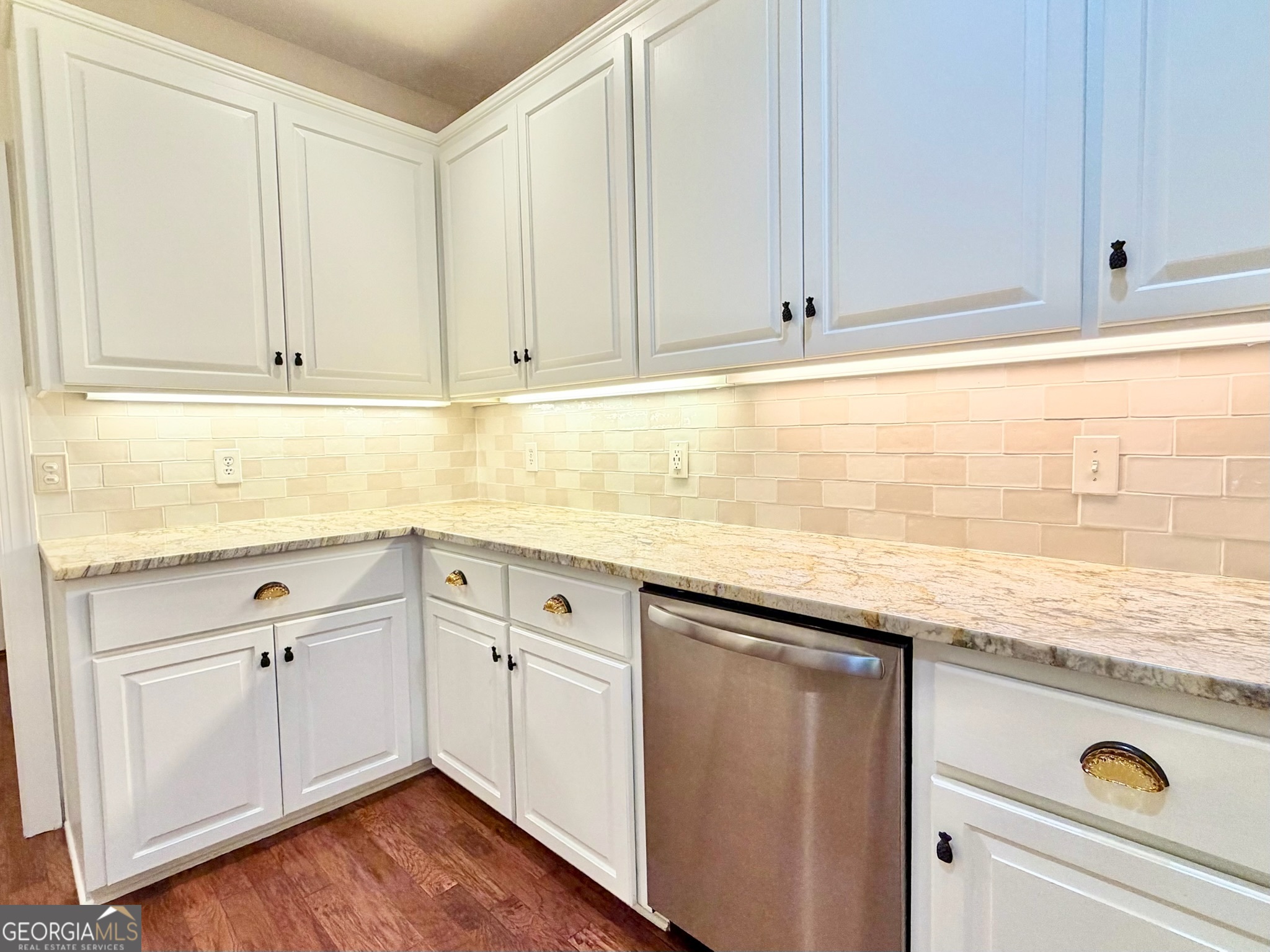 317 Commons Road St. Simons, GA 31522 - Photo 17 of 44 a kitchen with granite countertop cabinets sink and wooden floor