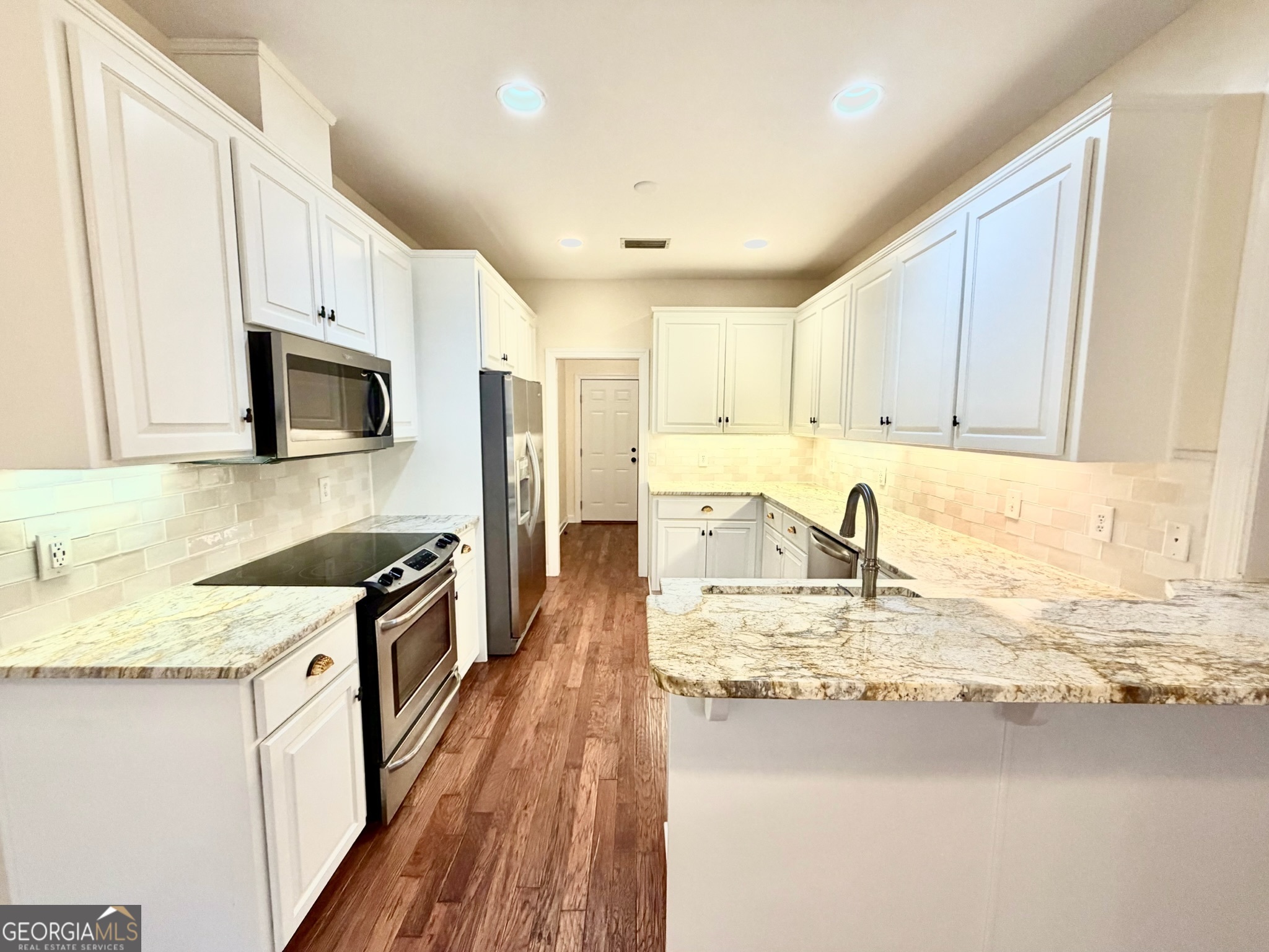 317 Commons Road St. Simons, GA 31522 - Photo 18 of 44 a kitchen with stainless steel appliances granite countertop a sink stove and refrigerator