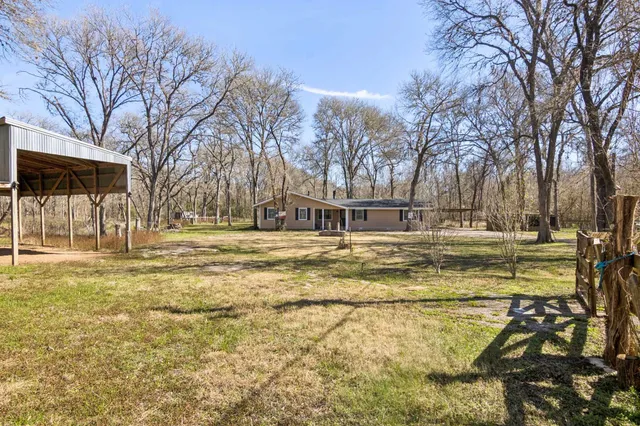 a row of dirt yard with large trees