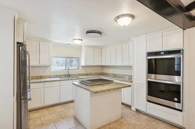 a kitchen with granite countertop a sink stainless steel appliances and white cabinets