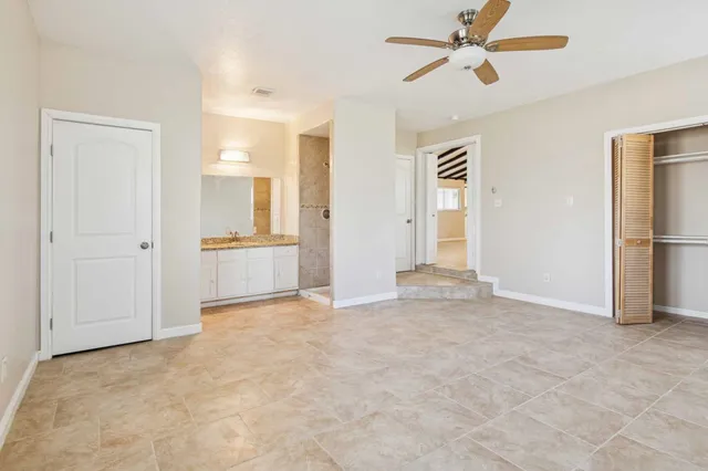 an empty room with chandelier fan and windows