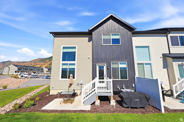 4646 Alder Drive, Unit 223 Mapleton, UT 84664 - Photo 21 of 35 Rear exterior featuring a concrete patio, wooden deck with white railings, and a two-story design with a mix of stucco and vertical plank siding