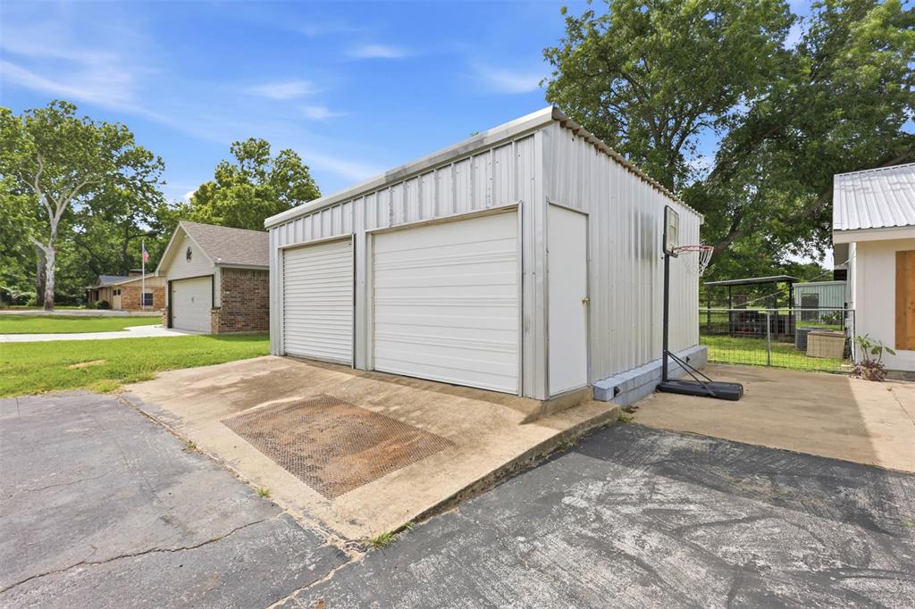 308 West 1st Street Springtown, TX 76082 - Photo 6 of 39 Detached metal building featuring two roll-up garage doors and a side entry door