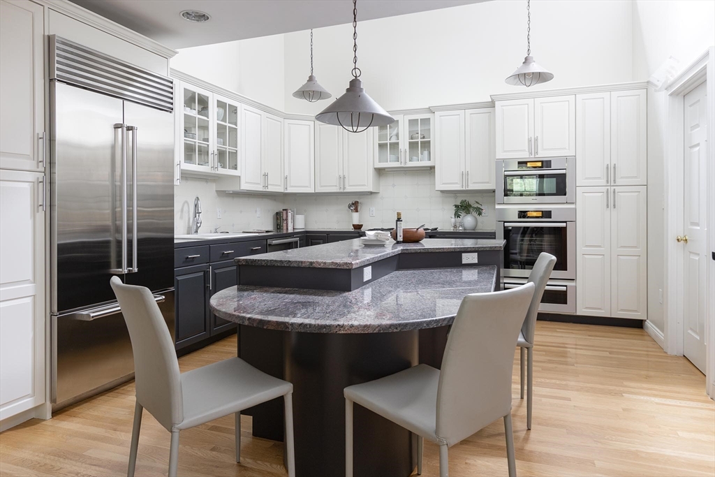 51 Rawson Road, Unit 51 Brookline, MA 02445 - Photo 10 of 23 a kitchen with stainless steel appliances granite countertop a sink a stove a refrigerator cabinets and a dining table with wooden floor