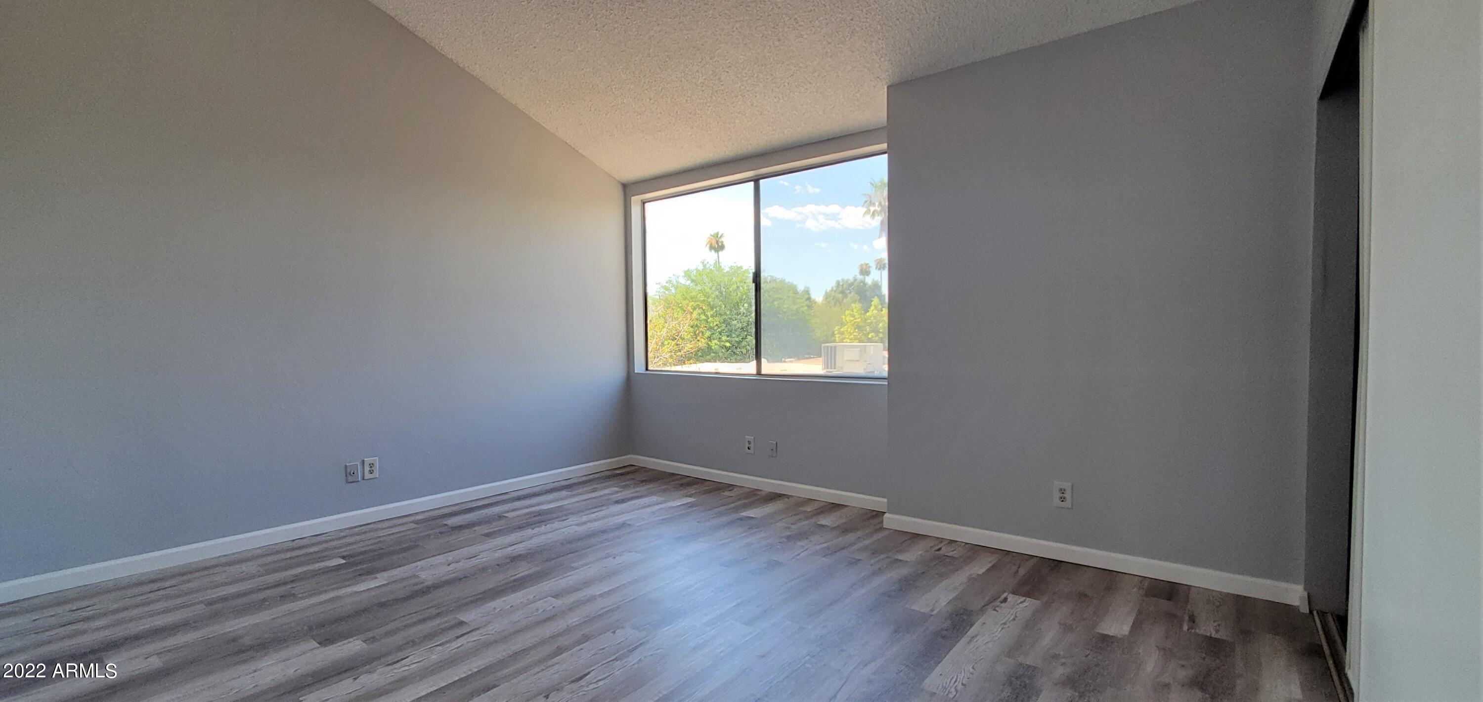 3411 North 12th Place, Unit 8 Phoenix, AZ 85014 - Photo 15 of 41 a view of an empty room with wooden floor and a window