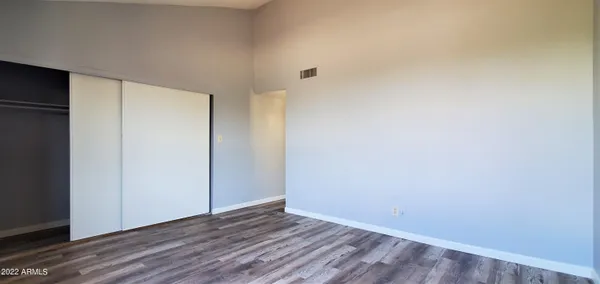 a view of an empty room with wooden floor and closet