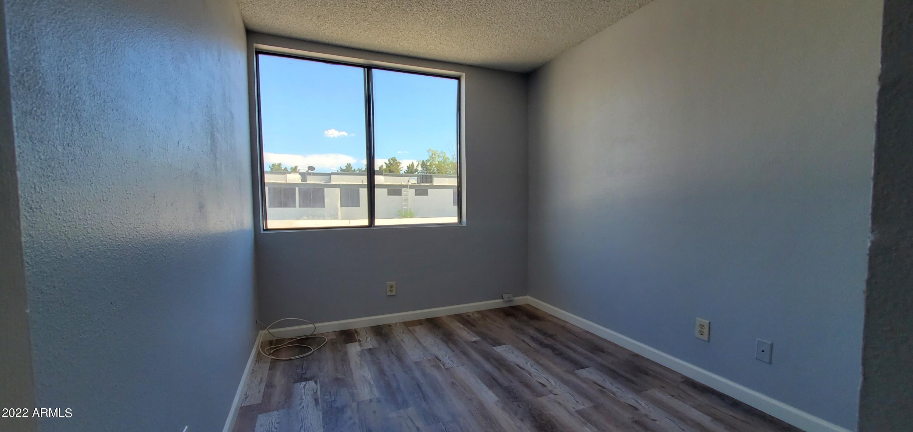 3411 North 12th Place, Unit 8 Phoenix, AZ 85014 - Photo 28 of 41 a view of an empty room with wooden floor and a window