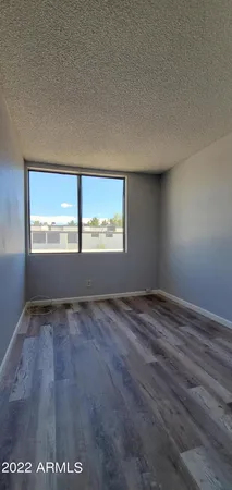 a view of an empty room with closet and wooden floor