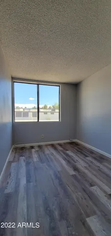 a view of an empty room with closet and wooden floor