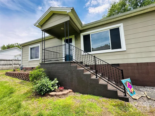 a view of a house with a small yard and a wooden bench