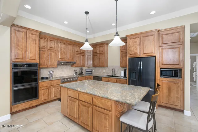 a kitchen with stainless steel appliances granite countertop a sink a stove a refrigerator cabinets and a kitchen island