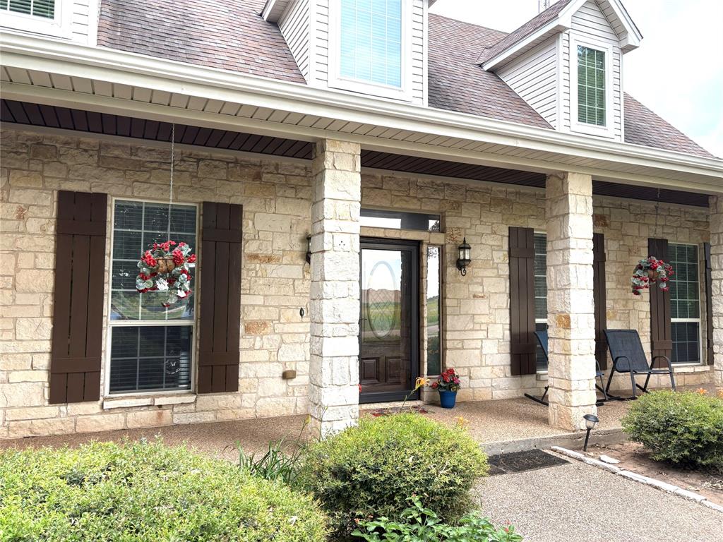 1170 Brazos Loop Gholson, TX 76705 - Photo 4 of 37 Stone veneer facade with prominent dormer windows, a covered front porch, and dark wood shutters