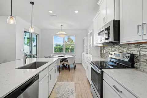 a kitchen with granite countertop a sink a counter space appliances and cabinets