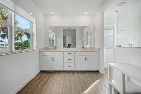 a spacious bathroom with a double vanity sink a mirror and a shower