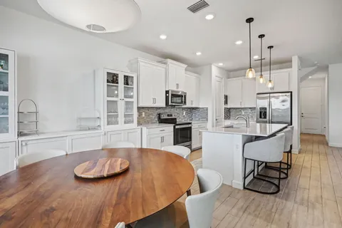 a kitchen with stainless steel appliances kitchen island granite countertop a wooden floor and white cabinets