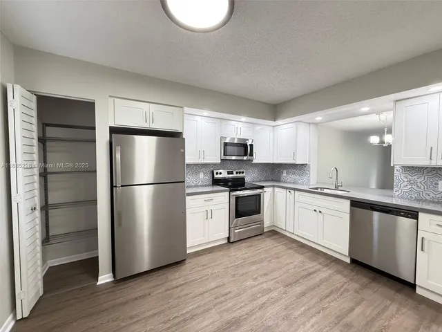 a kitchen with a refrigerator cabinets and wooden floor
