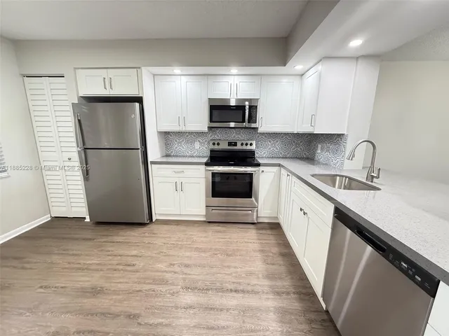 a kitchen with a sink a microwave a refrigerator and cabinets