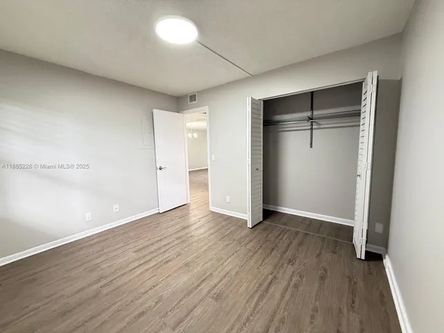 an empty room with wooden floor and closet area
