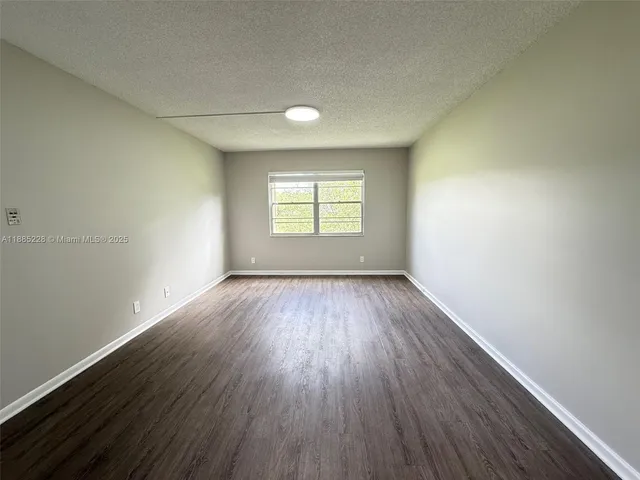 an empty room with wooden floor and window