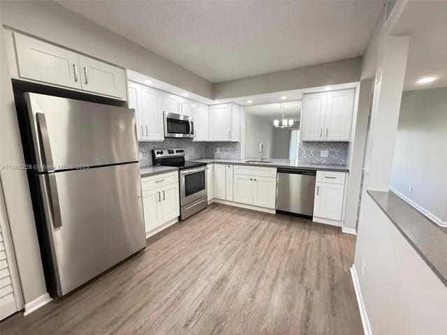 a kitchen with stainless steel appliances granite countertop a refrigerator a sink and a stove