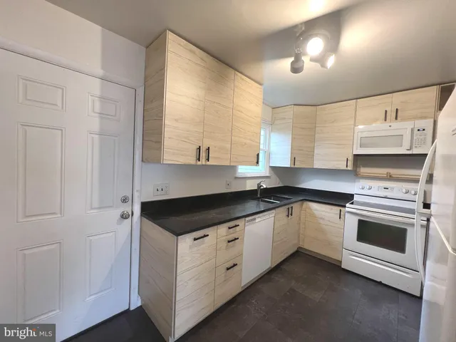 a kitchen with granite countertop white cabinets and white appliances