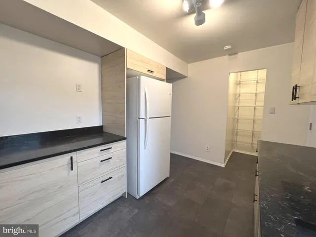 a kitchen with white cabinets and refrigerator