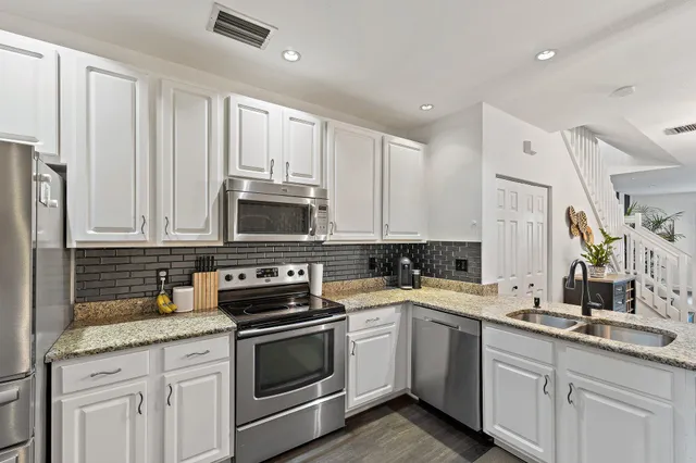 a kitchen with stainless steel appliances granite countertop a sink a stove a refrigerator and cabinets