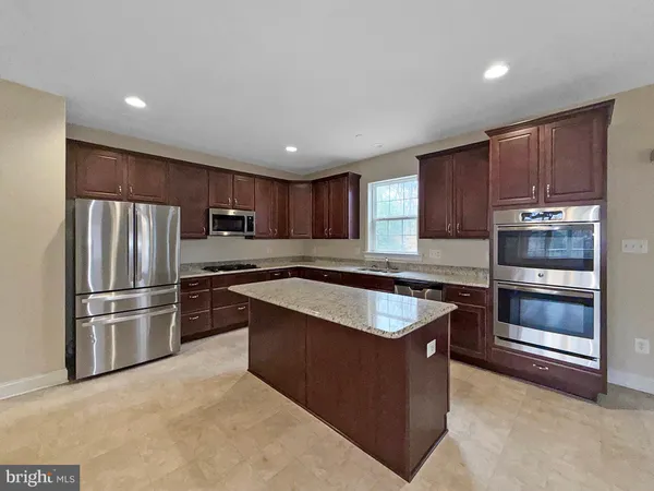 a kitchen with kitchen island granite countertop stainless steel appliances and refrigerator