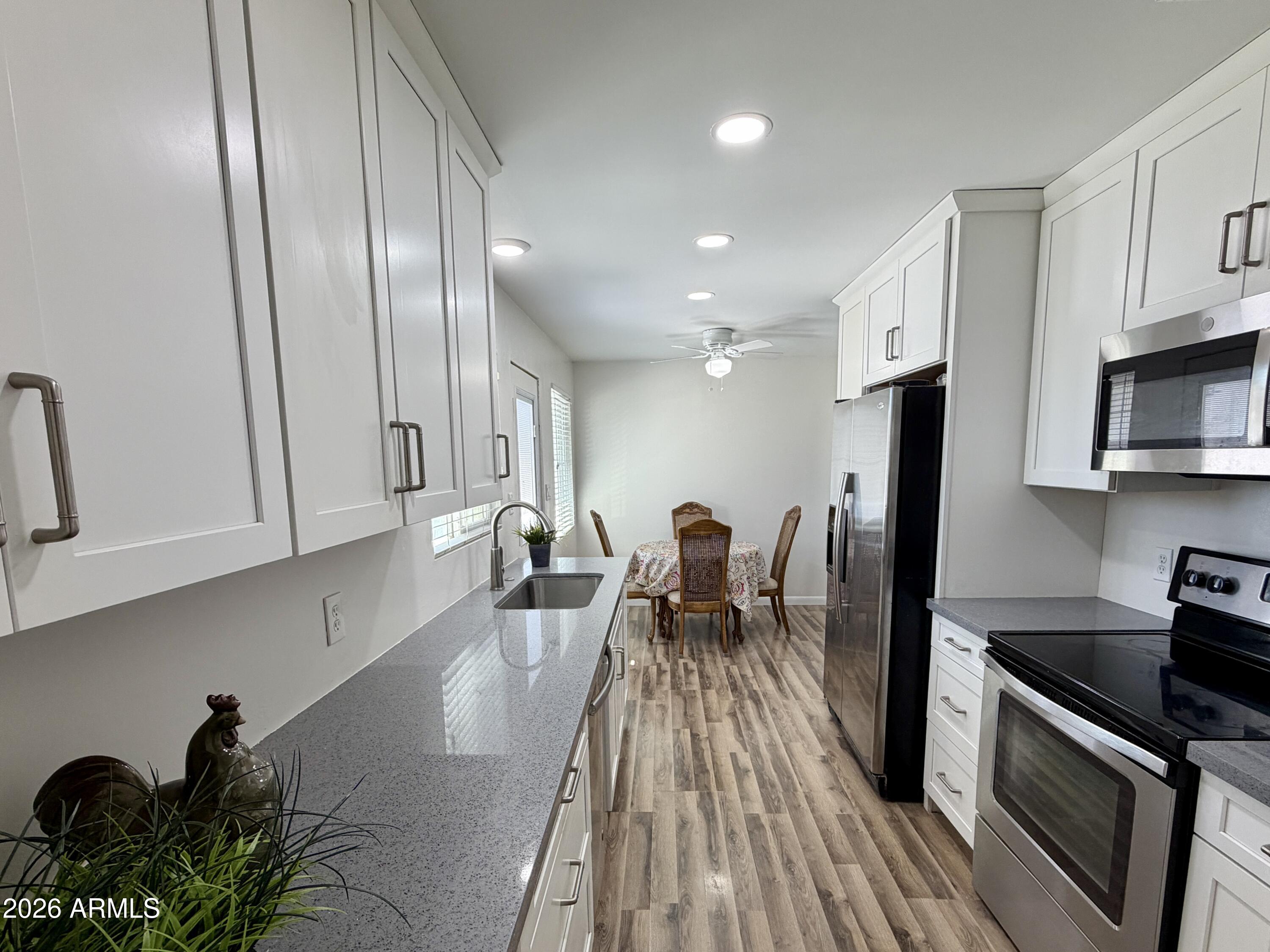 543 West 18th Street Tempe, AZ 85281 - Photo 7 of 29 a kitchen with stainless steel appliances a refrigerator a stove a sink dishwasher and white cabinets with wooden floor
